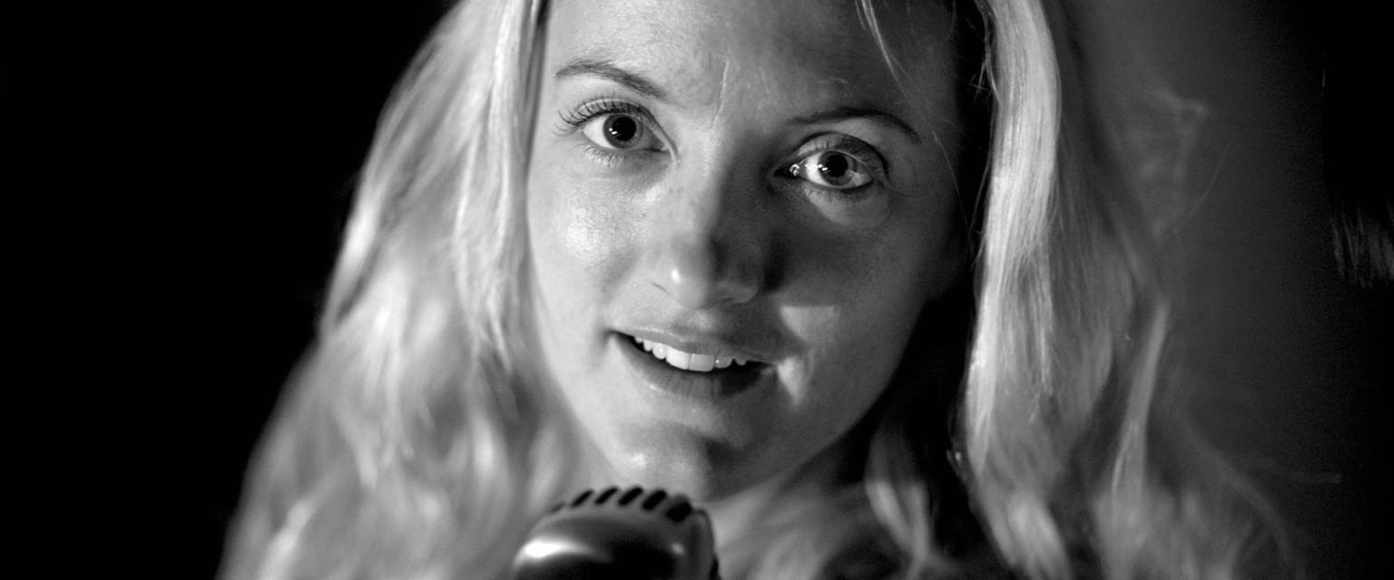 Portrait noir et blanc de Dorothée Pousséo, comédienne voix off Sonacom, les yeux écarquillés, au micro vintage