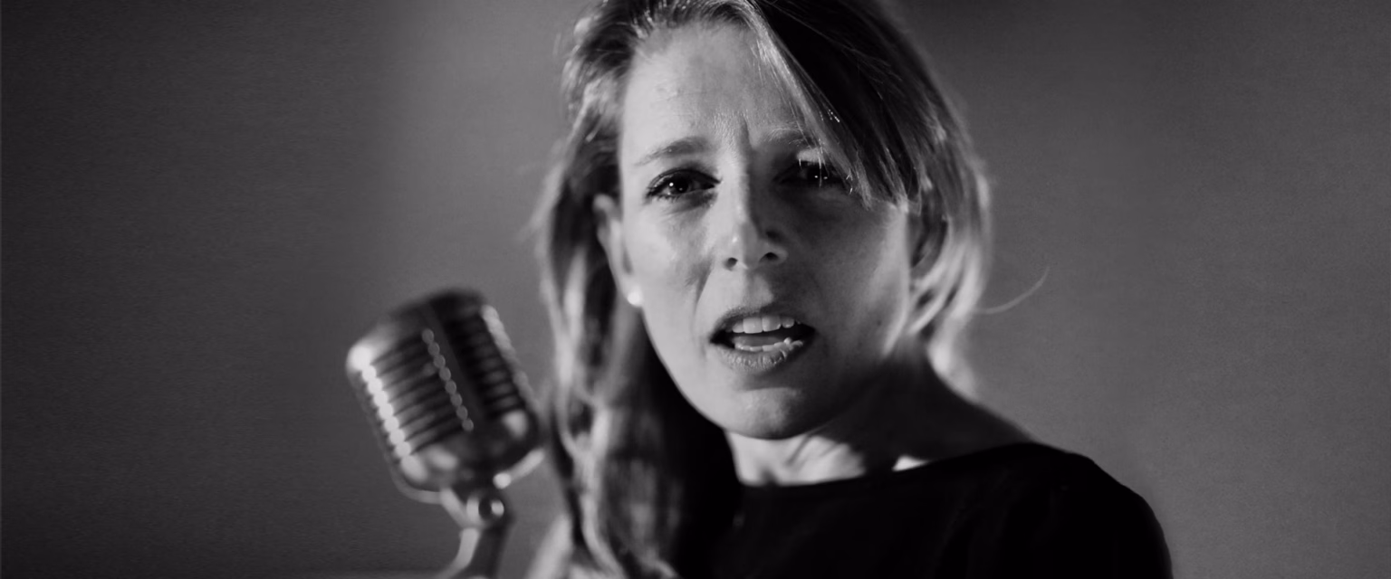 Portrait noir et blanc d'Emma Darmon, comédienne voix off Sonacom, en pleine prise de voix, au micro vintage