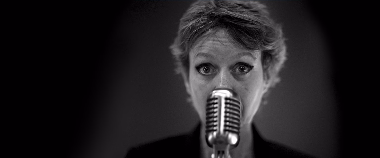 Portrait noir et blanc d'Isabelle Benhadj, comédienne voix off Sonacom, face au micro vintage