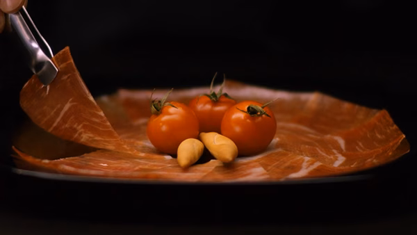 Tranches de jambon Serrano et tomates cerises sur une assiette, publicité digitale par Sonacom