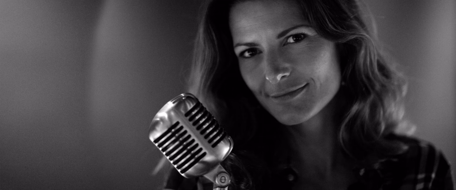 Portrait noir et blanc de Marie Zidi, comédienne voix off Sonacom, souriante, au micro vintage