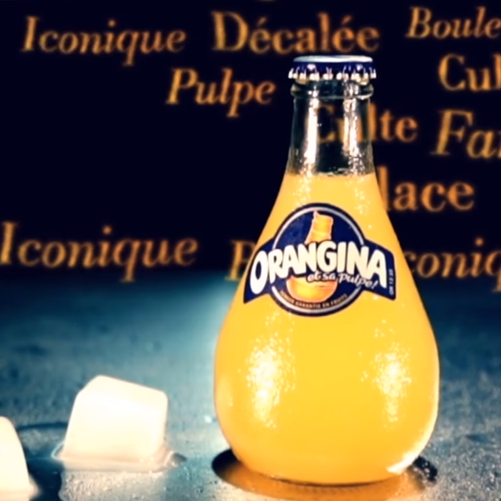 Bouteille d'Orangina cernée des mots iconique, décalée, pulpe, film de marque BtoB par Sonacom