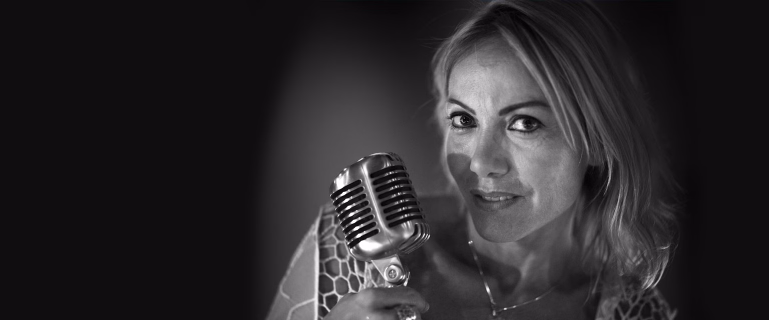 Portrait noir et blanc de Sandrine Fougère, comédienne voix off Sonacom, le regard droit, au micro vintage