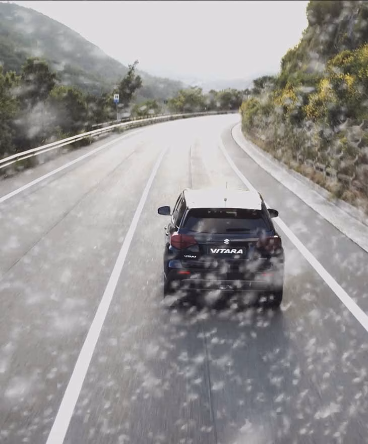 Suzuki Vitara sur une route de montagne sous la pluie, adaptation française des spots par Sonacom