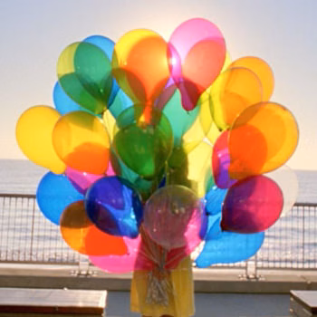Bouquet de ballons multicolores sur une terrasse face à la mer, spots TV Transitions par Sonacom